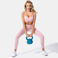 Blush and Bold women's pink seamless yoga set with crop top and high-waist leggings, performing a kettlebell squat.